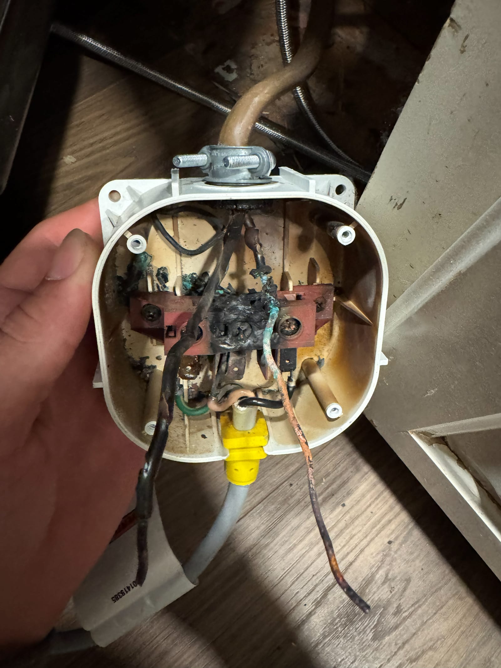 A ceiling box removed from a home showing conductors burnt black, melted insulation and corroded copper from a failed connection