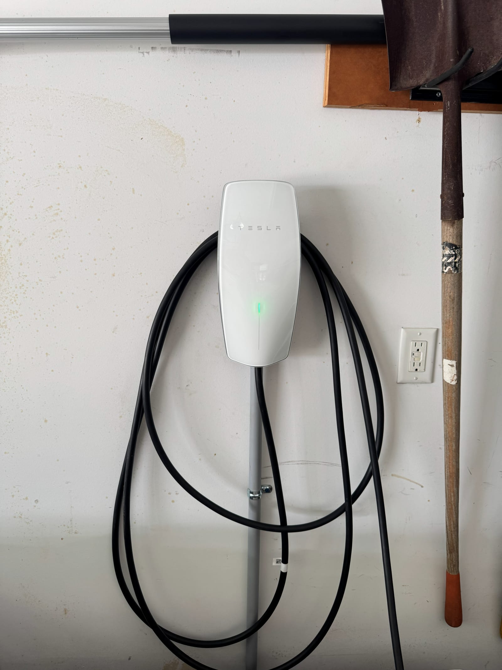 Level 2 electric vehicle wall charger installed in a garage with the charging cable coiled neatly beside it