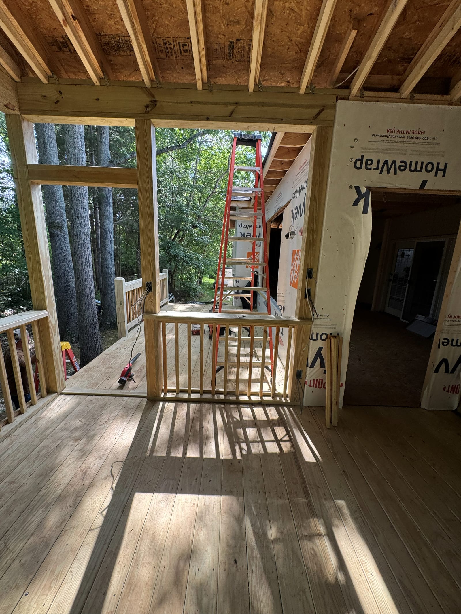 Screened porch addition mid-build, framing and house wrap visible where it joins the existing home