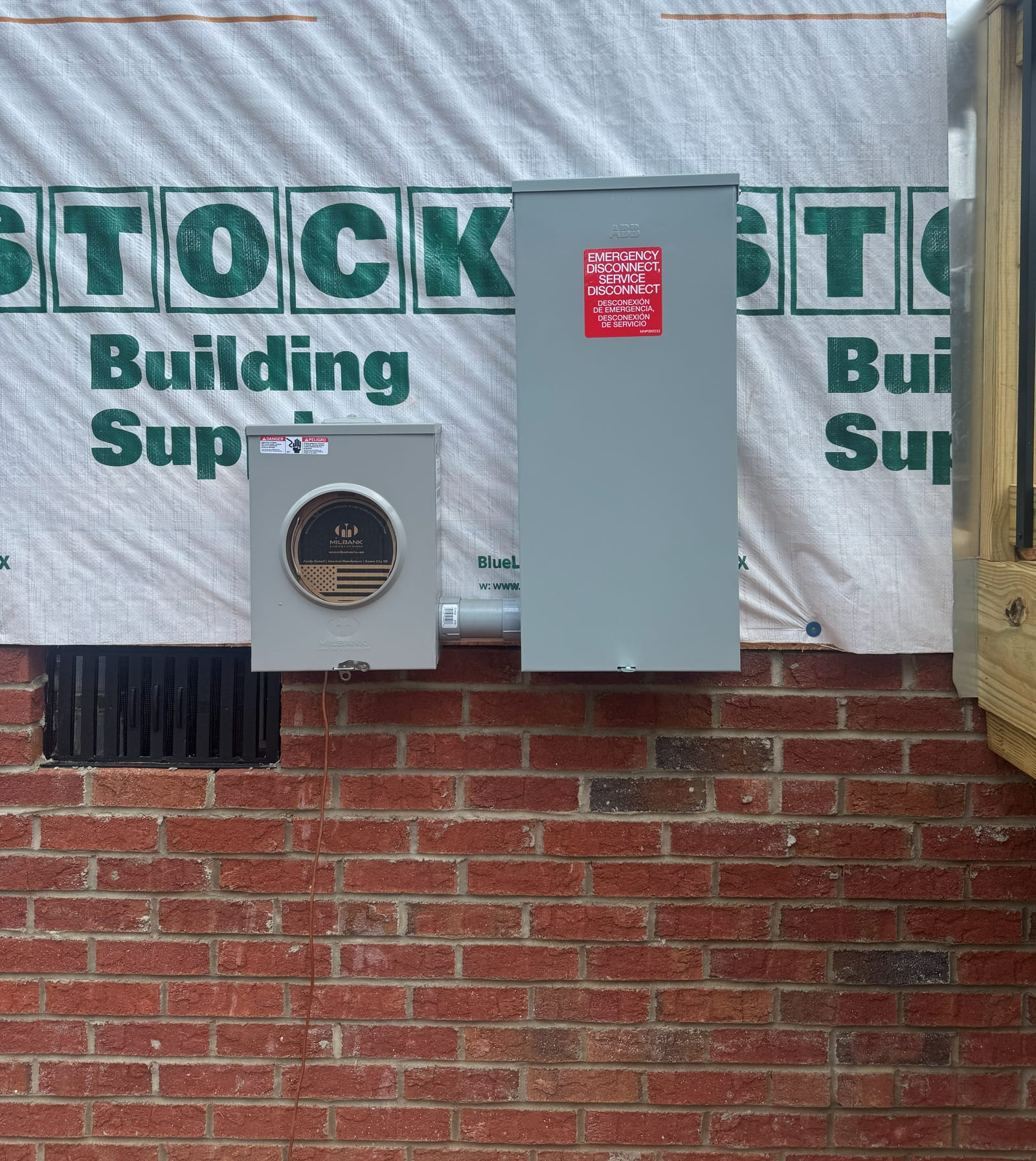 New meter base and service disconnect mounted on the brick exterior of a house under construction